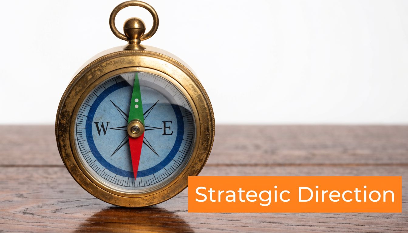 A vintage brass compass resting on a wooden surface next to an orange Strategic Direction banner.