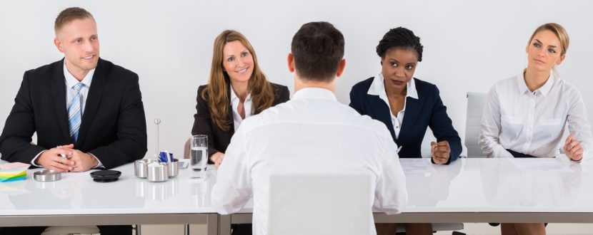 Group Of Businesspeople Interviewing Man In Office
